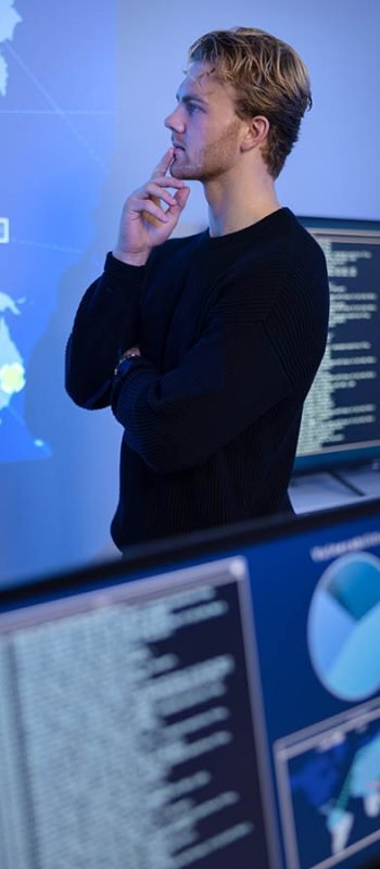 Thoughtful Cyber Security Control Center Operator Working. Multiple Screens Showing Technical Data and Alerts. Thoughtful cyber security analyst in a cyber security operations center (SOC). Multiple screens showing map, incident logs and alert data.